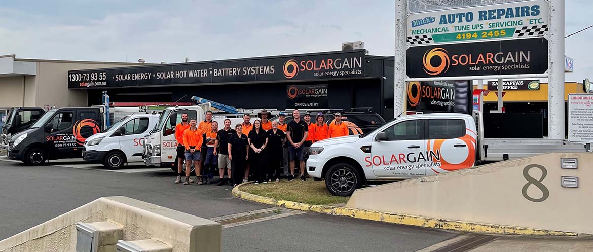Solargain team posing with branded vehicles outside their solar energy service center