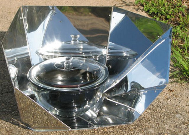 Solar cooker using reflective panels to concentrate sunlight and heat glass pots for outdoor cooking.