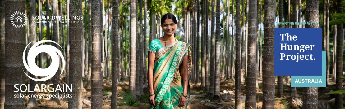 Girl in green sari standing in forrest symbolising partnership with Solargain, Solar Dwellings and The Hunger Project.